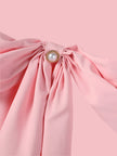 Close-up of a pink dress with a bow and pearl detail, brand 'ZANZEA' visible.