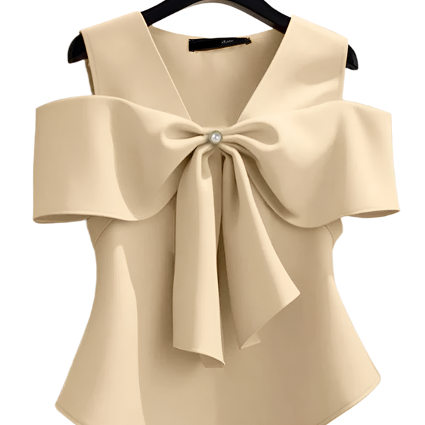 Beige blouse with a large bow detail on a hanger against a neutral background