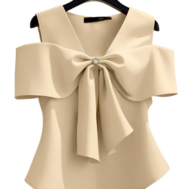 Beige blouse with a large bow detail on a hanger against a neutral background