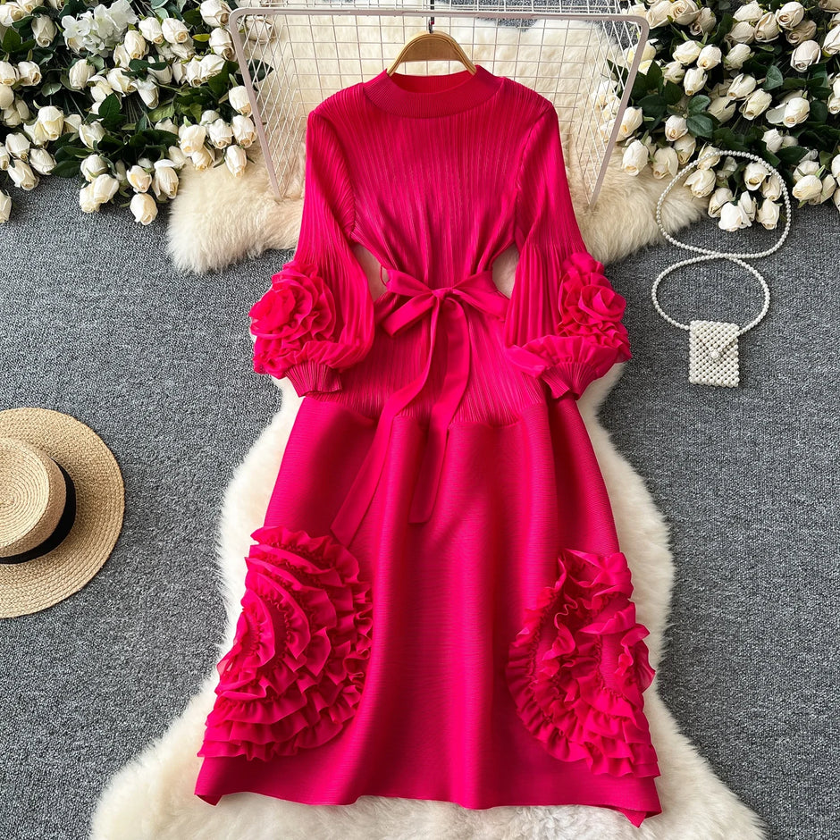 Pink dress with ruffled sleeves and bottom on a gray surface with decorative elements.