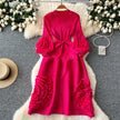 Pink dress with ruffled sleeves and bottom on a gray surface with decorative elements.