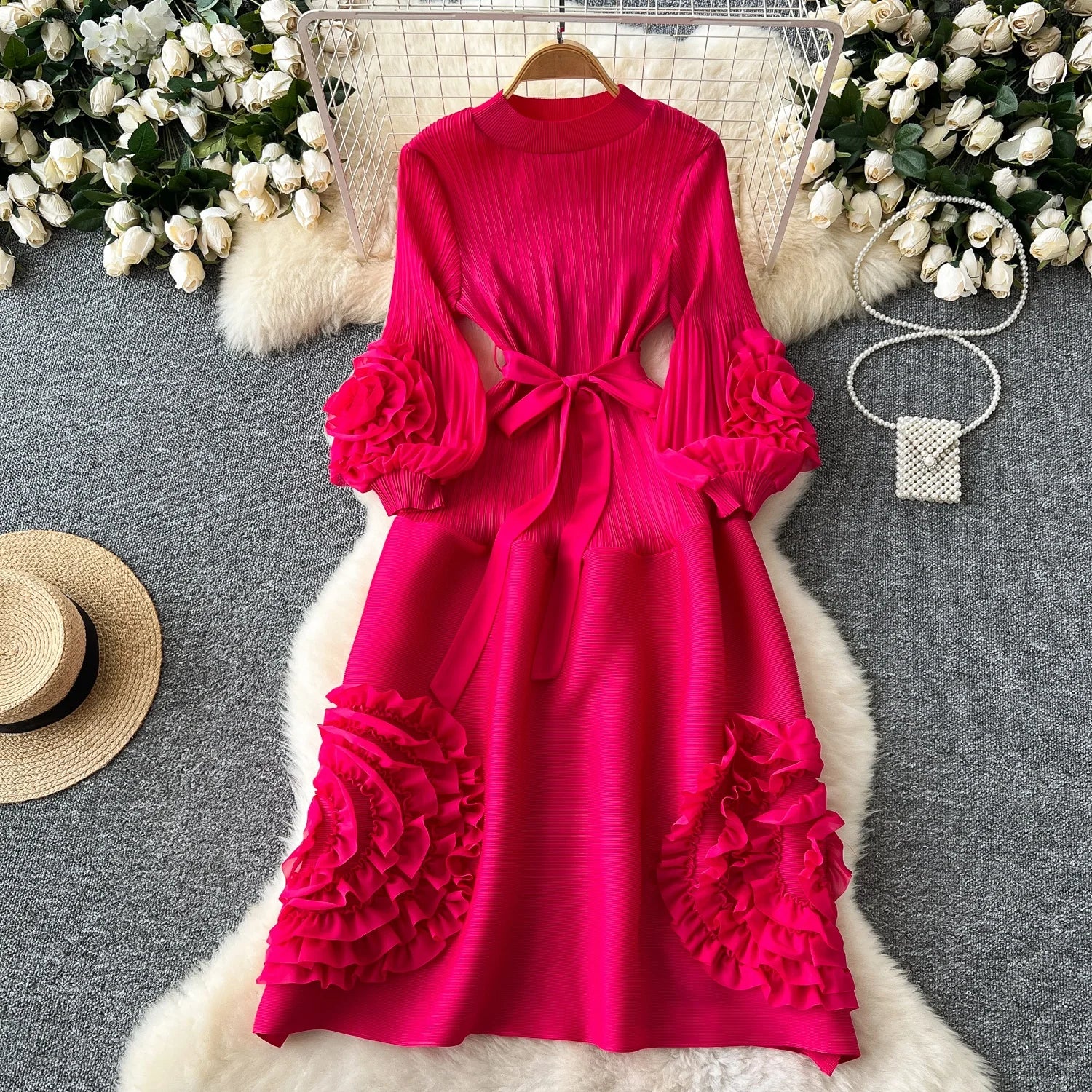 Pink dress with ruffled sleeves and bottom on a gray surface with decorative elements.