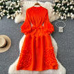Orange dress with ruffled sleeves and skirt on a gray surface with decorative elements.