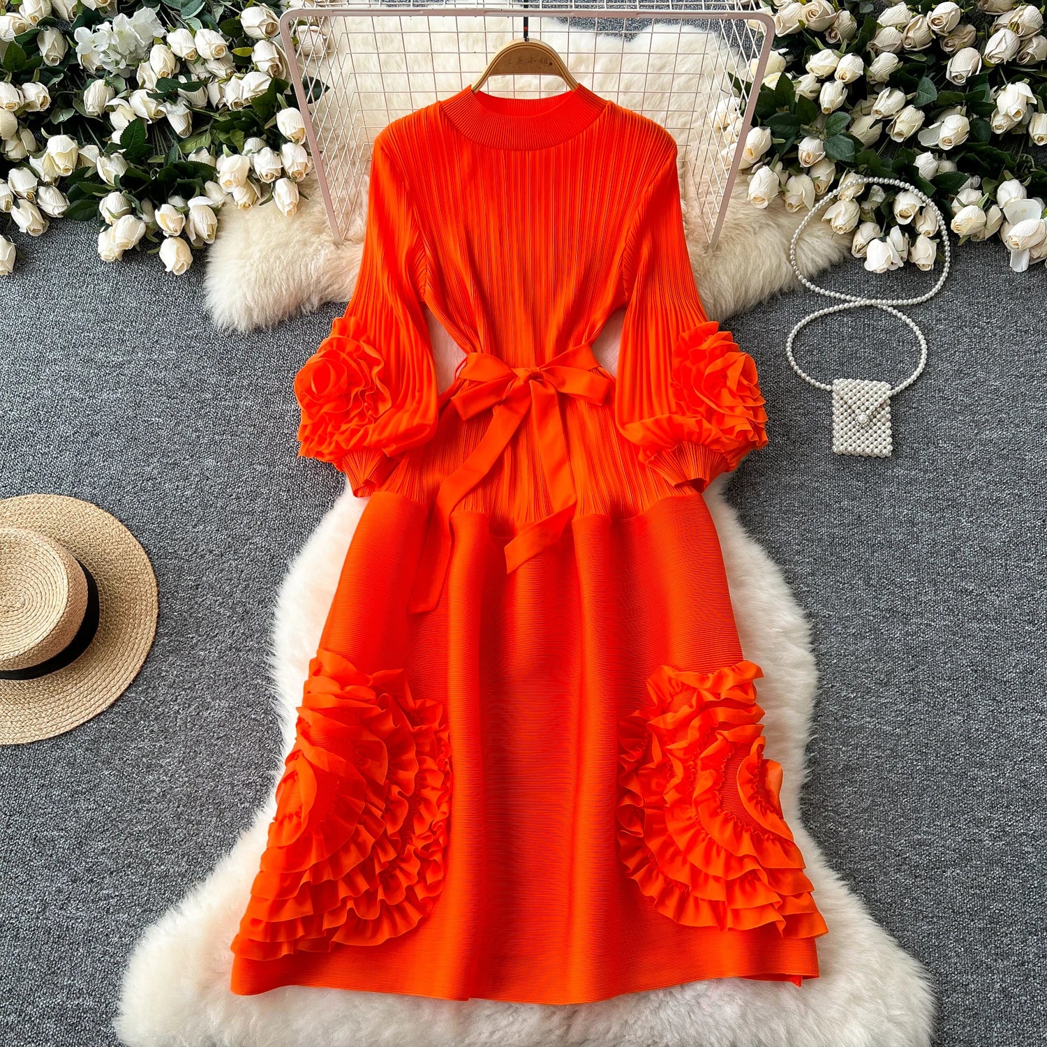 Orange dress with ruffled sleeves and skirt on a gray surface with decorative elements.