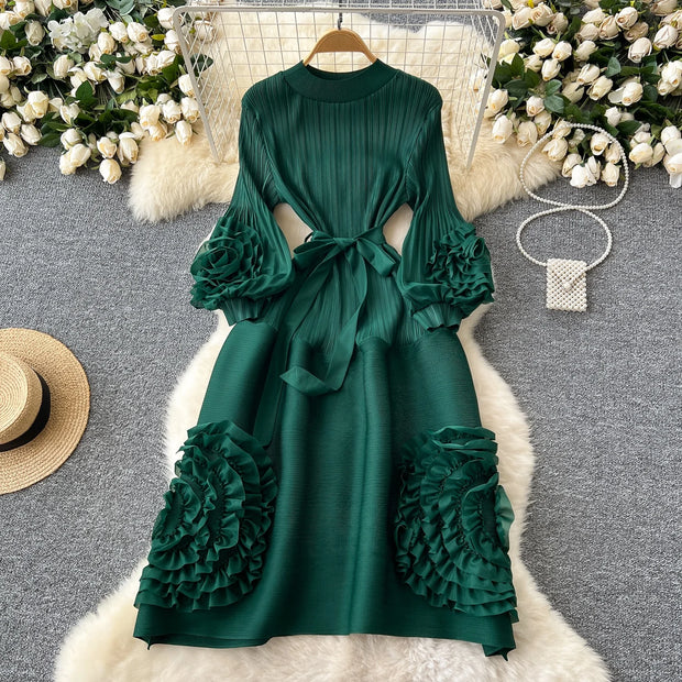 Green dress with ruffled sleeves and bottom on a gray surface with decorative elements.
