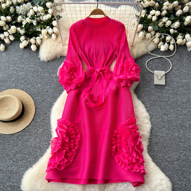 Pink dress with ruffled sleeves and bottom on a gray surface with decorative elements.