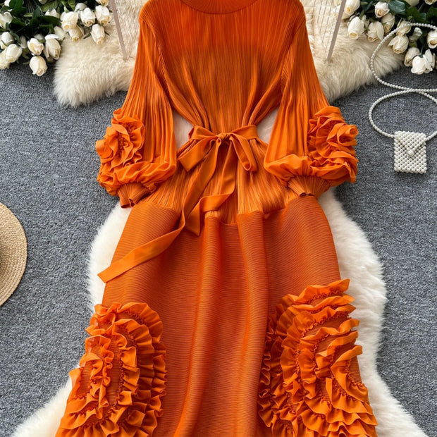 Orange dress with ruffled sleeves and bottom on a hanger against a decorative background.