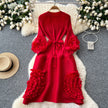Red dress with floral details on a gray surface with decorative elements
