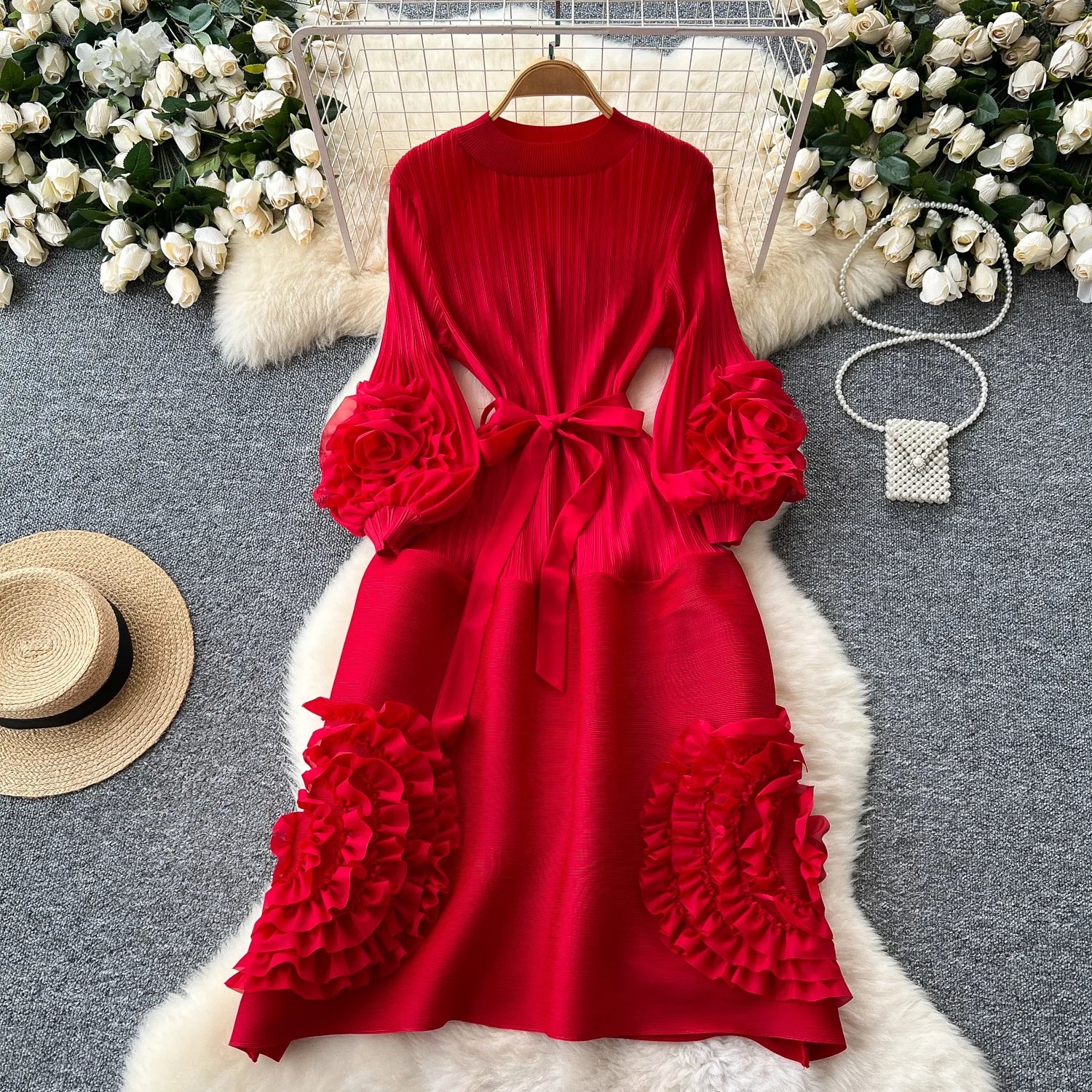Red dress with floral details on a gray surface with decorative elements