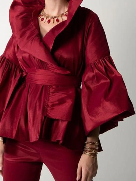 Red ruffled top and pants with gold jewelry on a plain background