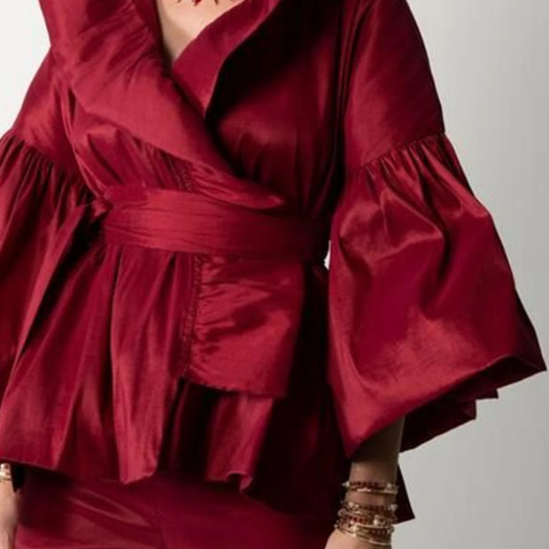 Red ruffled top and pants with gold jewelry on a plain background