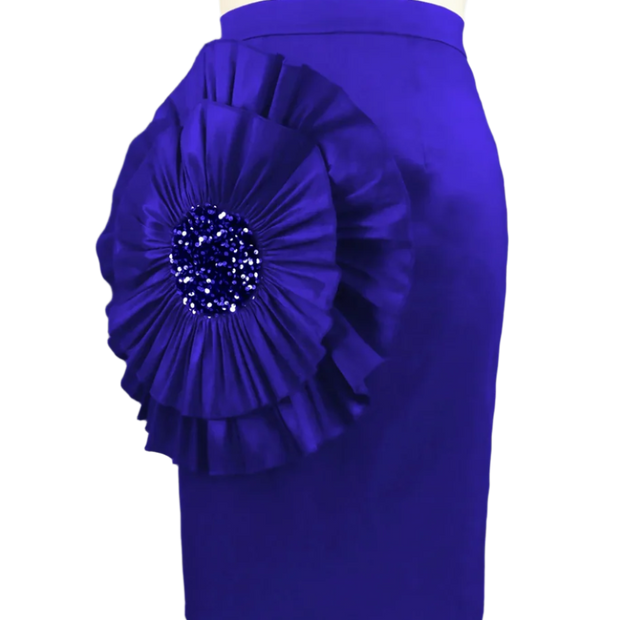 Blue skirt with a large floral embellishment on a mannequin against a gray curtain background
