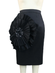 Black pencil skirt with a large floral embellishment on a mannequin against a gray curtain background