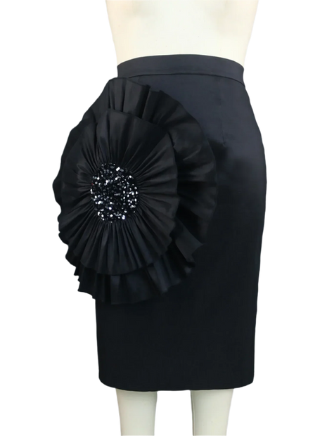 Black pencil skirt with a large floral embellishment on a mannequin against a gray curtain background