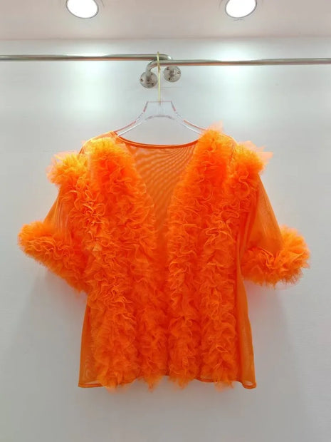 Orange ruffled top on a hanger against a white background