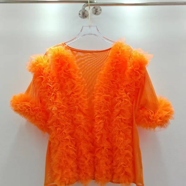 Orange ruffled top on a hanger against a white background