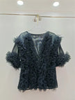 Black feathered top on a hanger against a white background