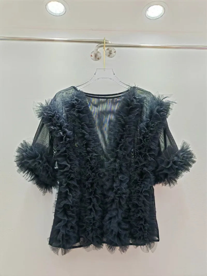 Black feathered top on a hanger against a white background