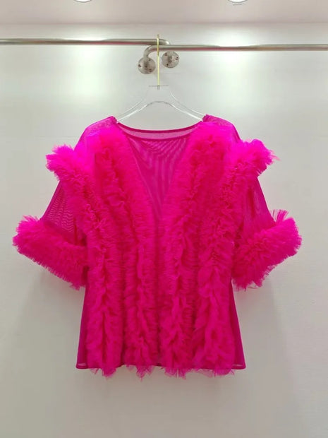 Hot pink feathered top on a hanger against a white background