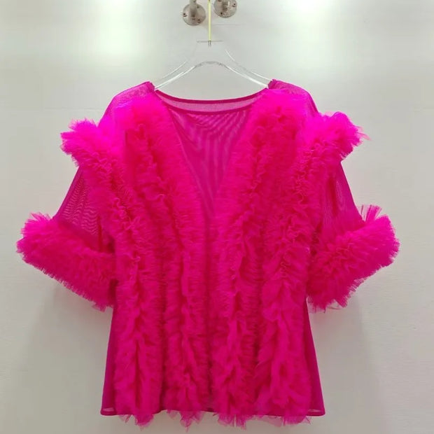 Hot pink feathered top on a hanger against a white background