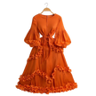 Orange dress with ruffled details on a hanger against a white background