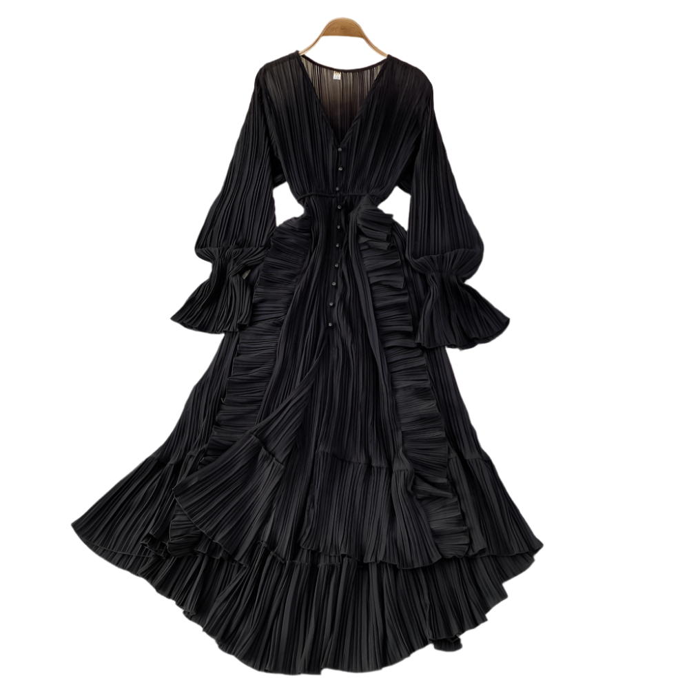 Black pleated dress on a hanger with decorative items on a gray surface