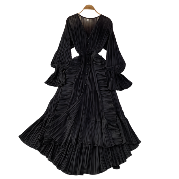 Black pleated dress on a hanger with decorative items on a gray surface