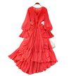 Red pleated dress on a hanger against a gray background