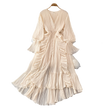Beige pleated dress on a hanger with decorative items on a gray surface