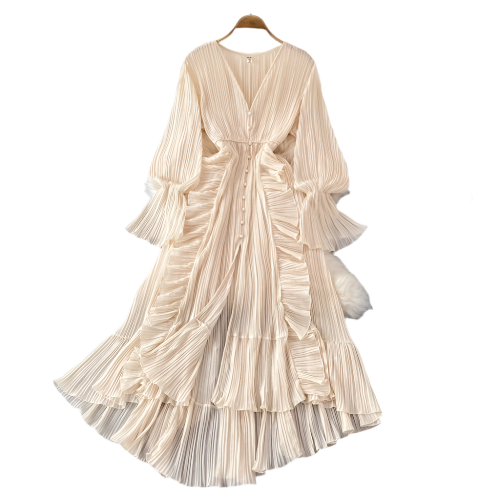 Beige pleated dress on a hanger with decorative items on a gray surface