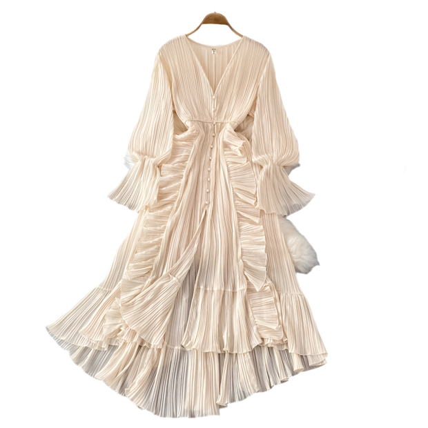 Beige pleated dress on a hanger with decorative items on a gray surface